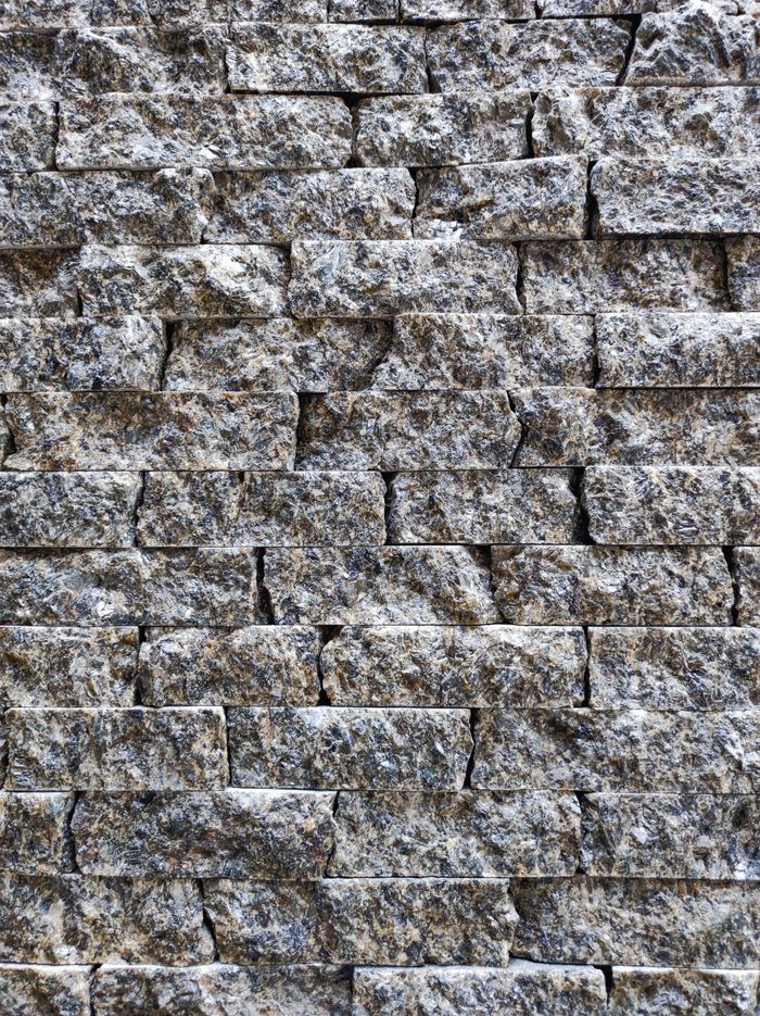 Close-up view of a rough textured stone wall, perfect for backgrounds.